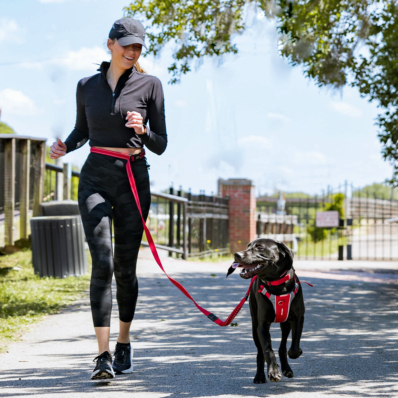 Woman running a black dog on a leash in an outdoor setting