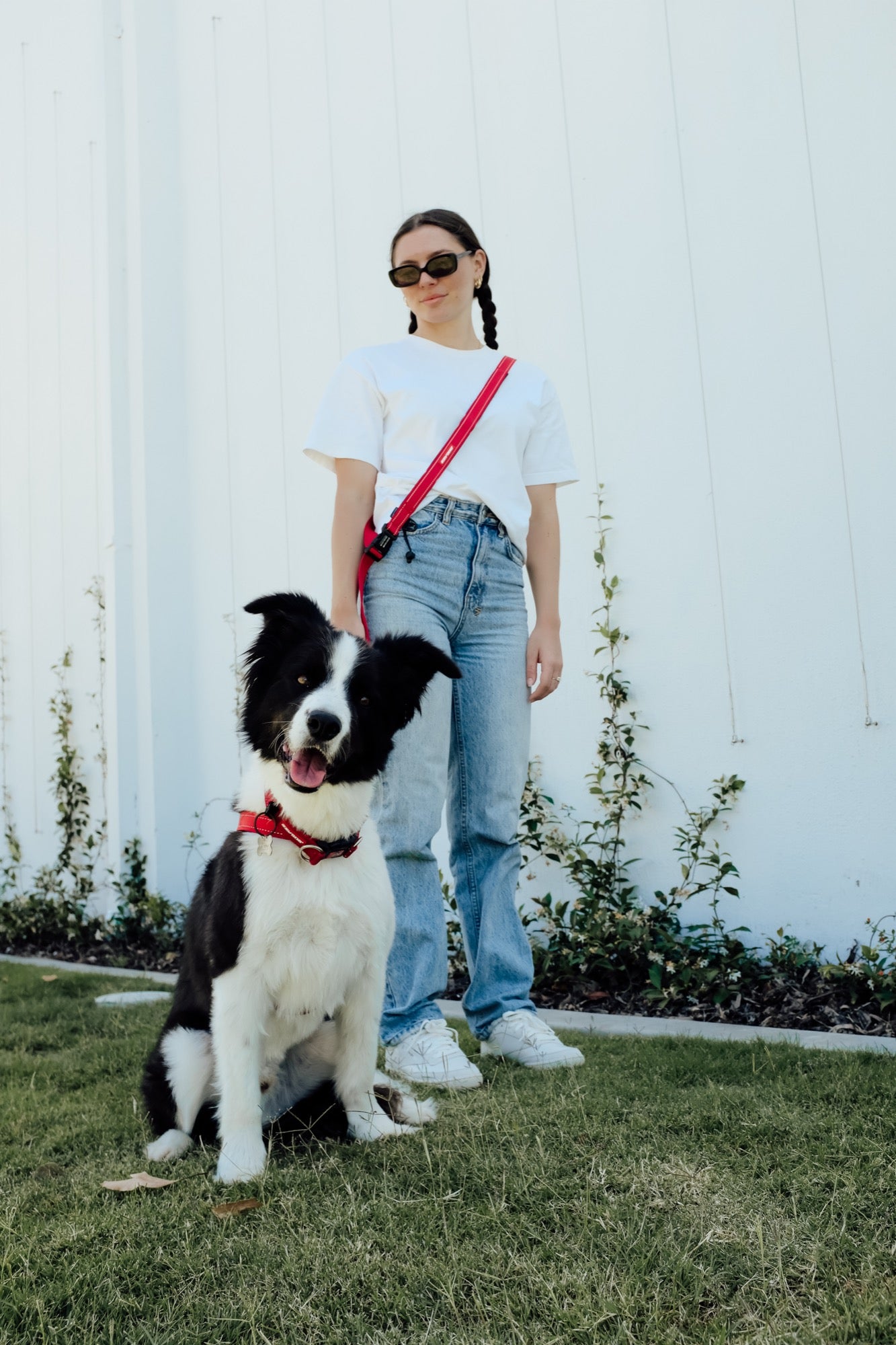 Woman standing with a dog on a leash in front of a white wall