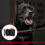 A black dog wearing a black leash with a metal ring, shown outdoors with a circular inset highlighting the leash attachment detail. Red text at the bottom reads 'FREE UPFRONT LEASH ATTACHMENT INCLUDED'.