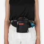 Person wearing a black waist bag with visible branding on a white background