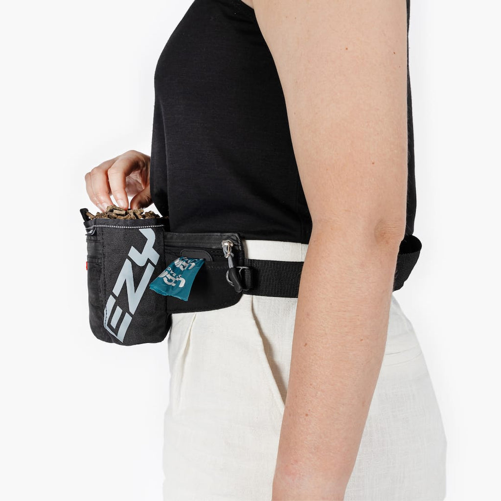 Person wearing a black waist bag with visible branding on a white background