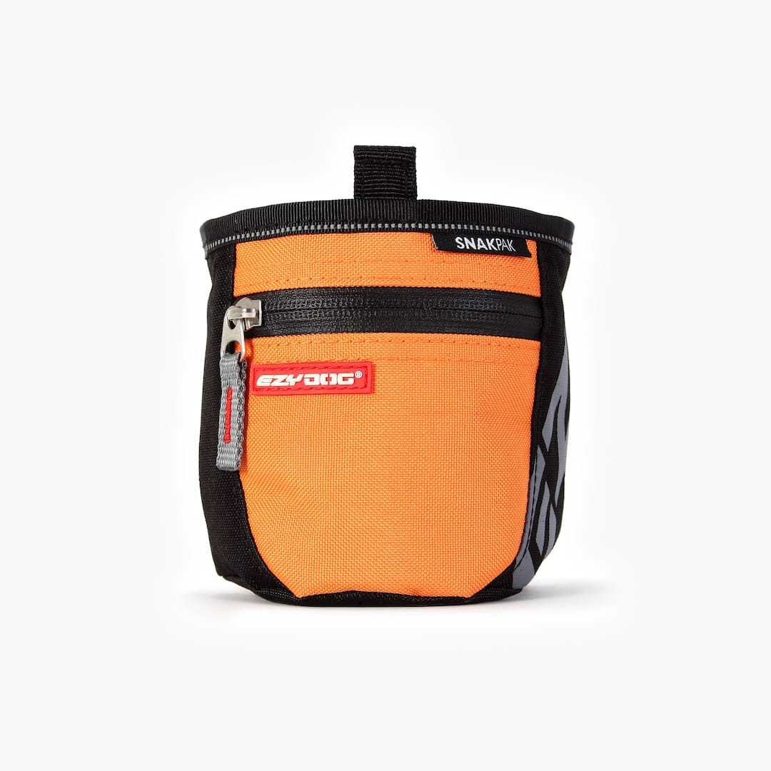 An orange SnakPak dog treat bag with magnetic closures and adjustable straps.