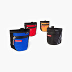 A collection of SnakPak dog treat bags in blue, red, orange, and black colors with magnetic closures and adjustable straps.